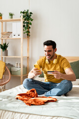 Man sitting on bed doing online shopping with smart phone.