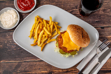Chicken burger with french fries and ketchup on wooden table