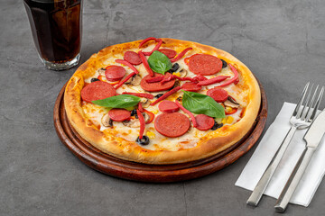 Mixed pizza with sausage, salami and mushrooms on a stone table