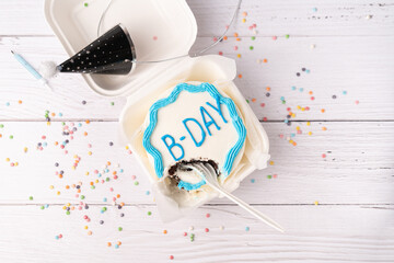 Flay lay with Half eaten Birthday mini cake on white table background with spoon.