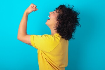 Profile photo of young arab woman wearing yellow T-shirt over blue background supporting soccer...