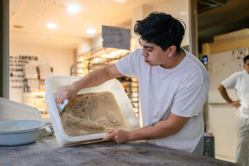 Baker taking dough out of a box - obrazy, fototapety, plakaty