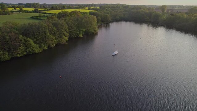Pull back aerial footage of Wroxham Broad, a body of water in the heart of the Norfolk Broads National Park. Captured on a bright summer evening just before the sun started to set
