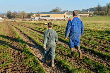 Agriculteur et son jeune fils marchant sur un chemin de la feme