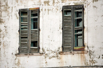 Old broken wooden windows on a dirty wall of an abandoned house