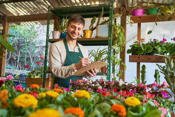 Florist in the flower shop with a checklist for an order