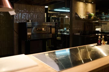 Foto op Plexiglas Workplace of chef or cook of pizzeria or luxurious restaurant with two bottles of flavoring on large table standing against electric oven © pressmaster