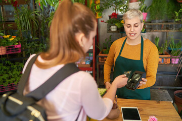 Customer in the flower shop makes mobile payment with a credit card