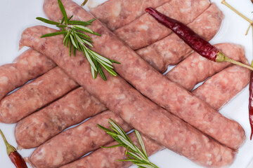 Raw sausages and spices on dish, fragment close-up