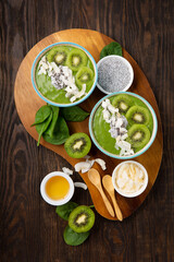 Green Smoothie Bowl with Spinach, Banana, Chia Seeds on Brown Background