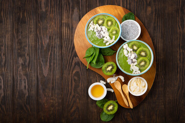 Green Smoothie Bowl with Spinach, Banana, Chia Seeds on Brown Background