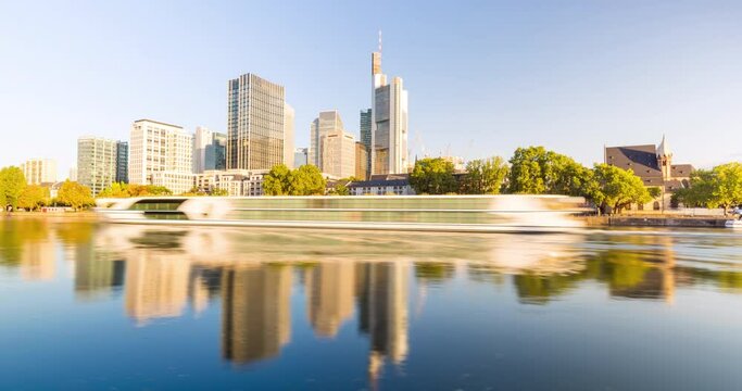 Frankfurt city skyline hyperlapse in 4k. Moving shot along the main river on a sunny day with blue sky. View of the iconic skyline of europes financial capital of the euro zone. 