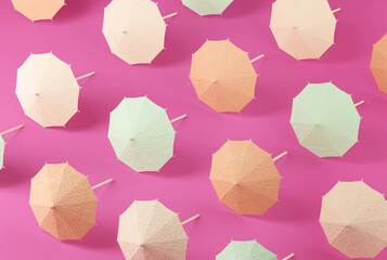 Bage, orange and green umbrellas pattern on pink background. Minimal summer concept.
