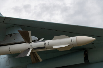 Fototapeta na wymiar Close-up view of Russian Air to air missile hanging under the wing of fighter aircraft. Soft focus. Military industry theme.