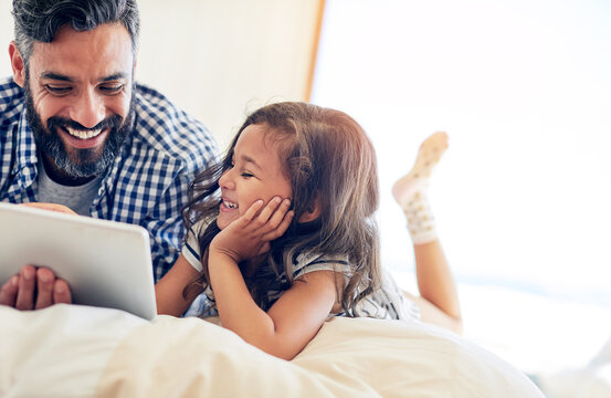 Love, man with daughter with tablet and happy in bedroom of their home. Family or bonding time, technology or communication and male parent with daughter smiling or laughing with entertainment - Powered by Adobe