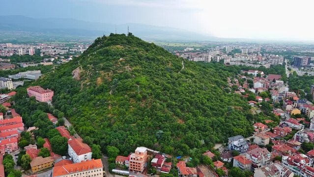 Town Plovdiv with houses and fields against backdrop of Rhodope Mountains and hills covered with forests and cloudy sky
