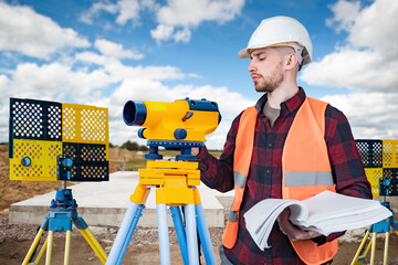 Man surveyor. Builder uses geodetic instrument. Surveyor at construction site. Geodetic equipment...