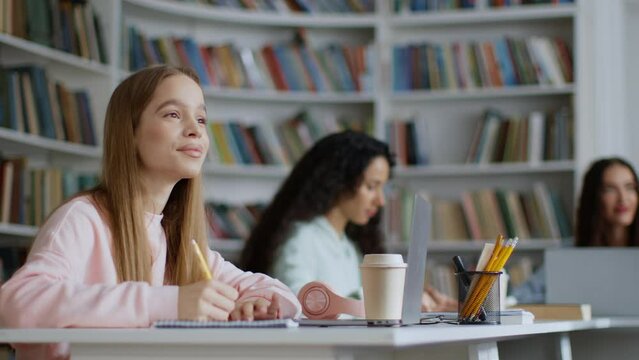 Group of pretty young ladies students listening to teacher at campus classroom, taking notes on subject, tracking shot