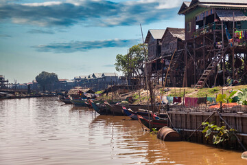 Houses on stilts and boats on rural river in Kampong Phluk floating fishing village, drought...