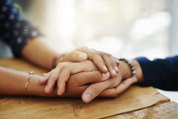 Holding hands, support and closeup with trust, solidarity and community on a home table. Therapy, diversity and gratitude of friends together with hope, respect and love for grief empathy and forgive - obrazy, fototapety, plakaty
