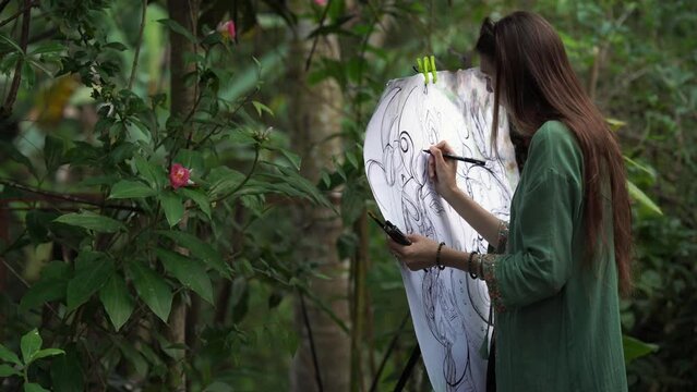 a young woman paints a landscape A young pretty woman artist paints paints a picture of a forest outdoors