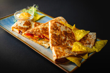 Tasty taco dish with sauce and tortillia chips on a side -  black background