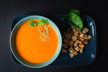 Top view- Beautiful orange cream pumpkin soup served with croutons - black background