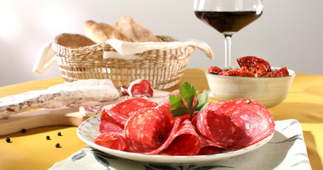 slices sausage salchichon on a plate. salami on a cutting board. cold cuts with bread and tomatoes. traditional spanish and italian sausages. meat delicacies antipasto on the table. 