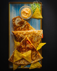 Tasty taco dish with sauce and tortillia chips on a side -  black background