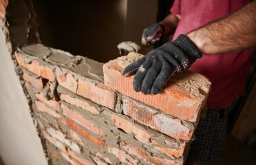 Close up of man hands in work glove laying brickwork in building under construction. Male worker...
