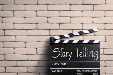 Storytelling  handwritten on clapperboard or film slate. white brick wall.