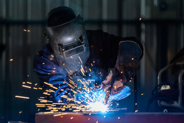 A technician or workers wearing industrial uniforms and welded iron mask at steel welding plants,...