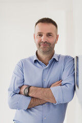 casual businessman wearing formal business clothes smiling at camera with crossed hands isolated over gray background.