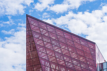 Glass Facade of Violet Tinted Semi-Transparent Glass Building Against Blue Sky with Sunbeams.