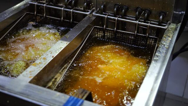 Cook putting chicken in frying oil in commercial restaurant
