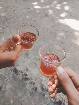 A pair of hands holding small glasses with liquid in them