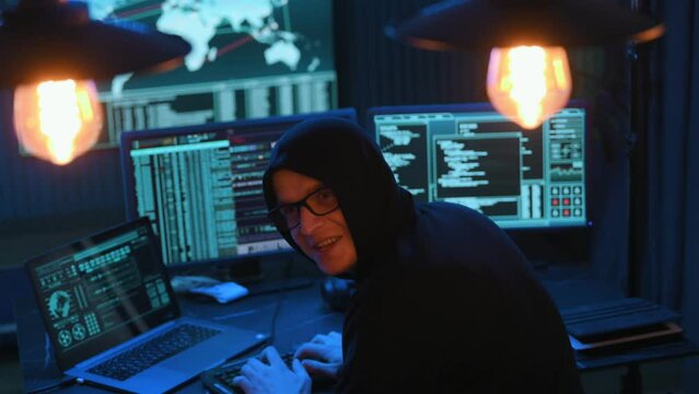 Having fun, pretending, having fun. Young professional male hacker is indoors by computer with lot of information on displays.