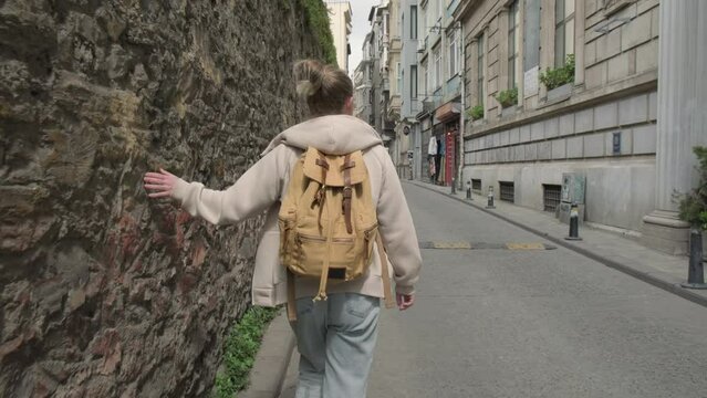 Woman tourist walking along narrow street of city.