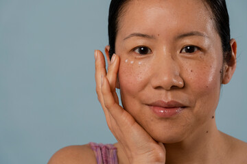 Portrait of mid adult woman applying cream under eyes