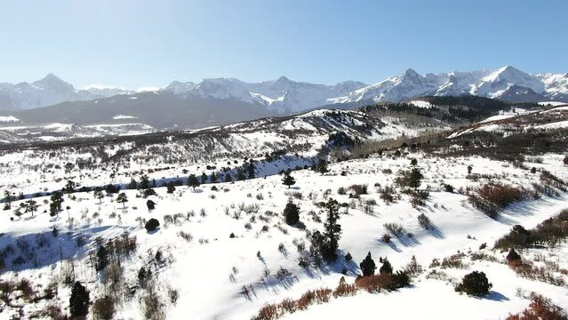 Aerial Cinematic drone mid winter of San Juan Mountain Range Ridgway Telluride 14er stunning ranching farm land of Colorado early morning mid winter blue sky pan forward up movement