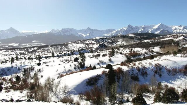 Aerial Cinematic drone mid winter of San Juan Mountain Range Ridgway Telluride 14er stunning ranching farm land of Colorado early morning mid winter blue sky pan to the right movement