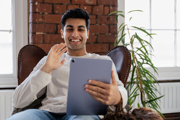 Smiling young man having video call on tablet