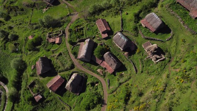 Aerial tilt up view of Pornacal Bra&ntilde;a hut cabin rural village in Somiedo valley, Asturias.