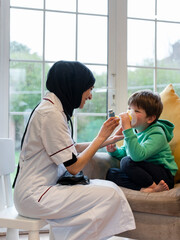 Doctor assisting boy using inhaler