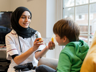 Female doctor demonstrating to boy how to use inhaler
