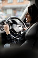 Young woman wearing hijab driving car © Cultura Creative