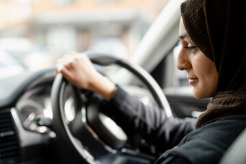 Young woman wearing hijab driving car © Cultura Creative