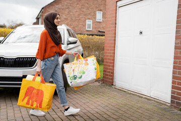 Woman wearing hijab returning home with shopping bags