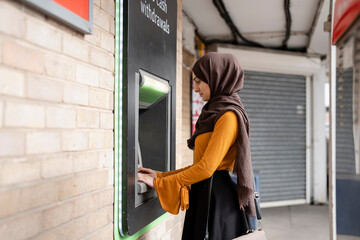 Woman in hijab using ATM