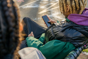 Young man sitting outdoors and using phone